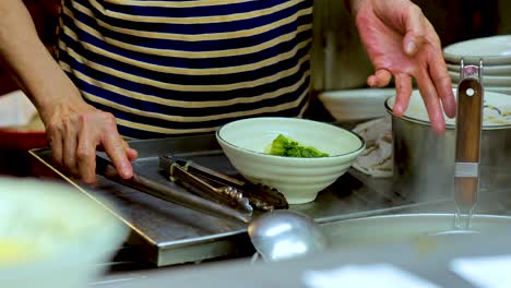 chef prepares noodle soup in hong kong kitchen