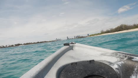 fpv de un kayak a la deriva en el océano hacia el horizonte de una ciudad