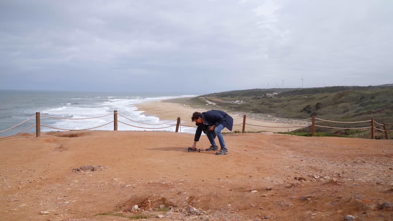 A young man doing pre take off checking for seagulls before flying drone on a scenic beach in nazare Portugal