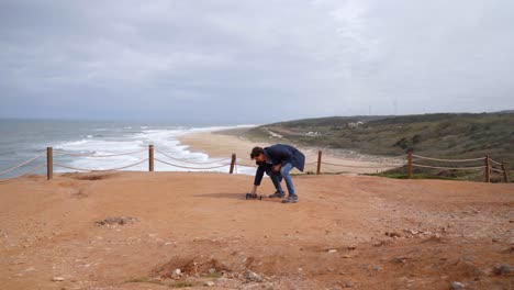 a young man doing pre take off checking for seagulls before flying drone on a scenic beach in nazare portugal