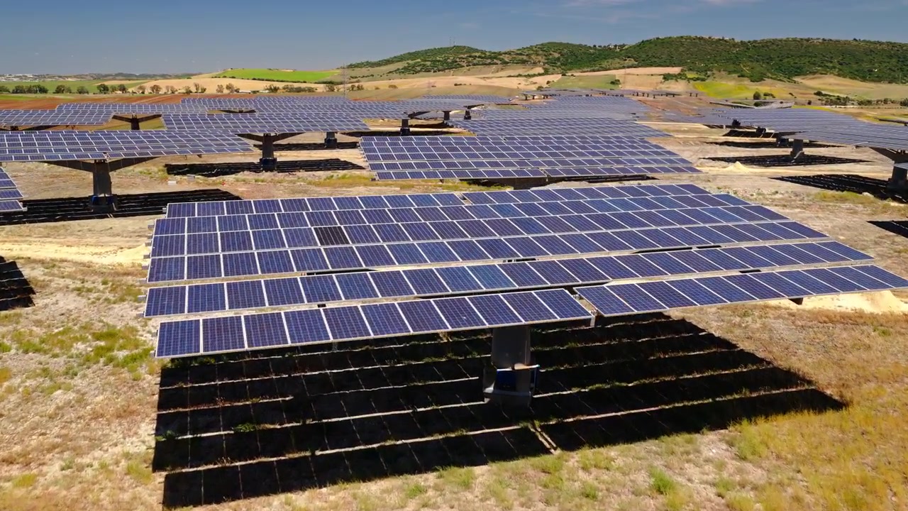 Filmisk droneoptagelse flyver over et stort solcelleanlæg med fotovoltaiske paneler, der genererer ren, vedvarende elektricitet. Bæredygtig energiinfrastruktur, der understøtter den globale energiovergang.