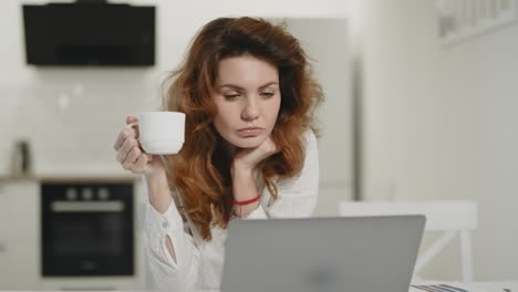 focused woman working laptop at open kitchen