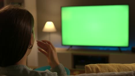 young woman eating popcorn and watching tv