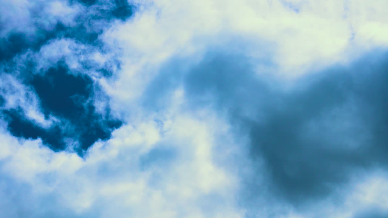 Dark Clouds Timelapse with Vivid Blue Sky Background. Contrast of Darker and Bright Cloud Layers. Dreamy Abstract Nature Footage.