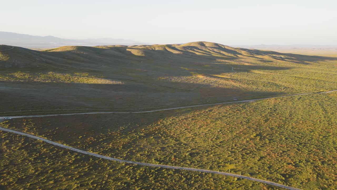 캘리포니아에서 슈퍼 꽃을 피우는 동안 그림자가 기어 다니는 언덕 위의 일몰의 공중 드론 타임  ⁇ 스