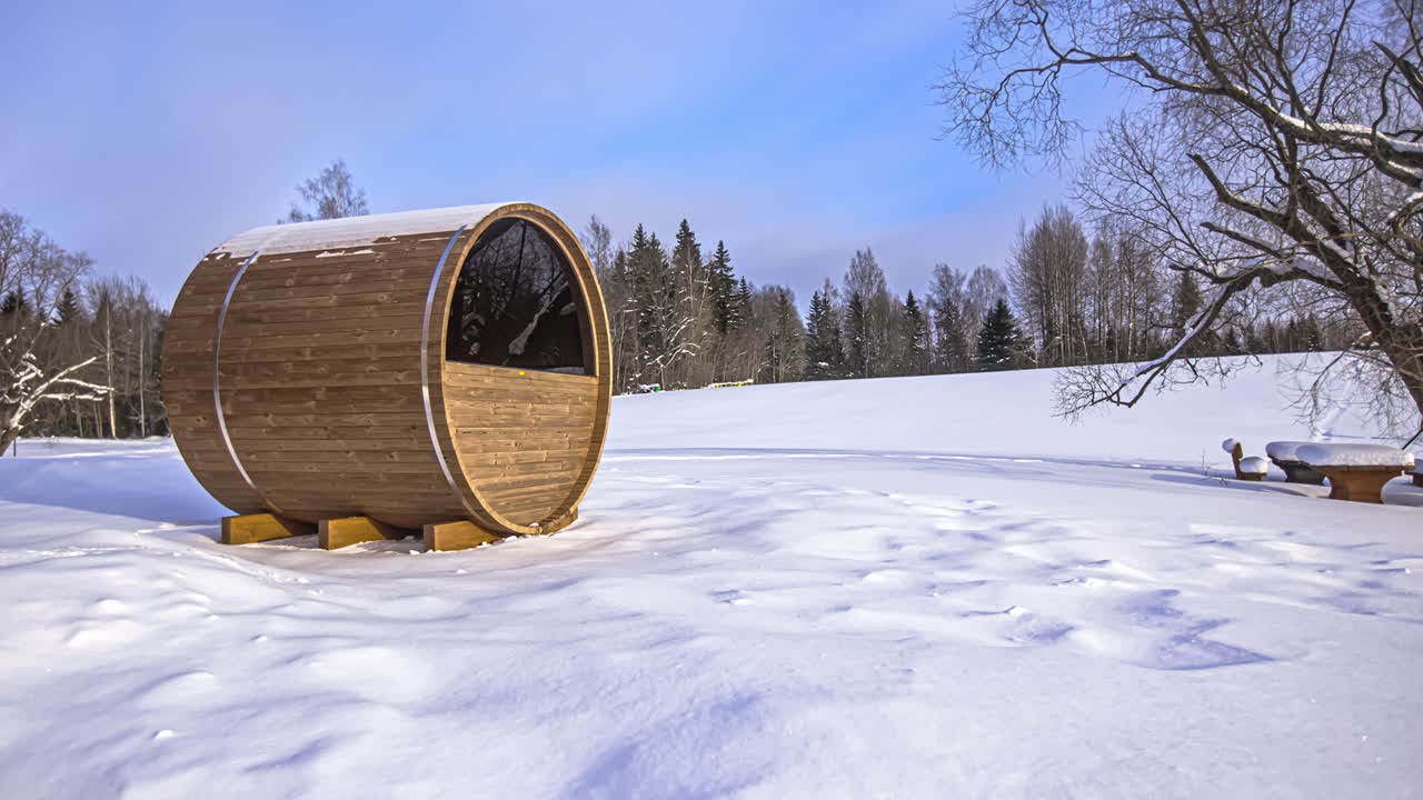 tiro de lapso de tiempo de sauna de barril de madera de pie en el paisaje de invierno cubierto de nieve durante las nubes voladoras en el cielo