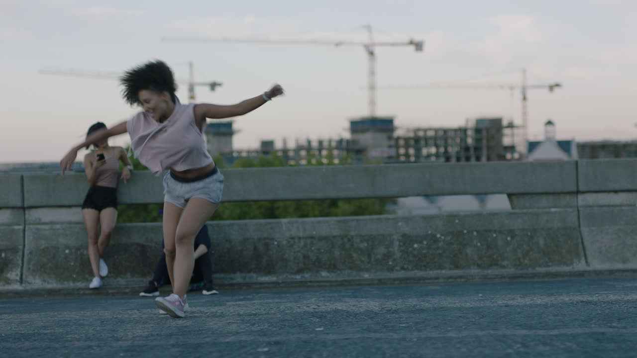 mujer bailando atractiva joven bailarina de raza mixta realizando baile de calle de estilo urbano en la ciudad practicando movimientos de estilo libre amigos viendo disfrutando pasar el rato juntos al atardecer