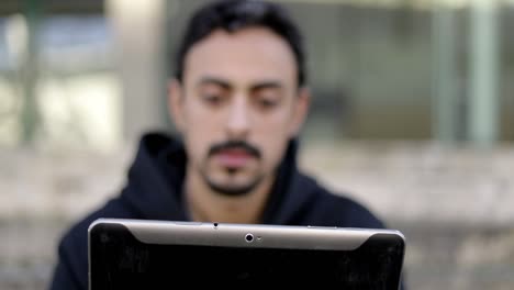 hombre serio usando una tableta en la calle