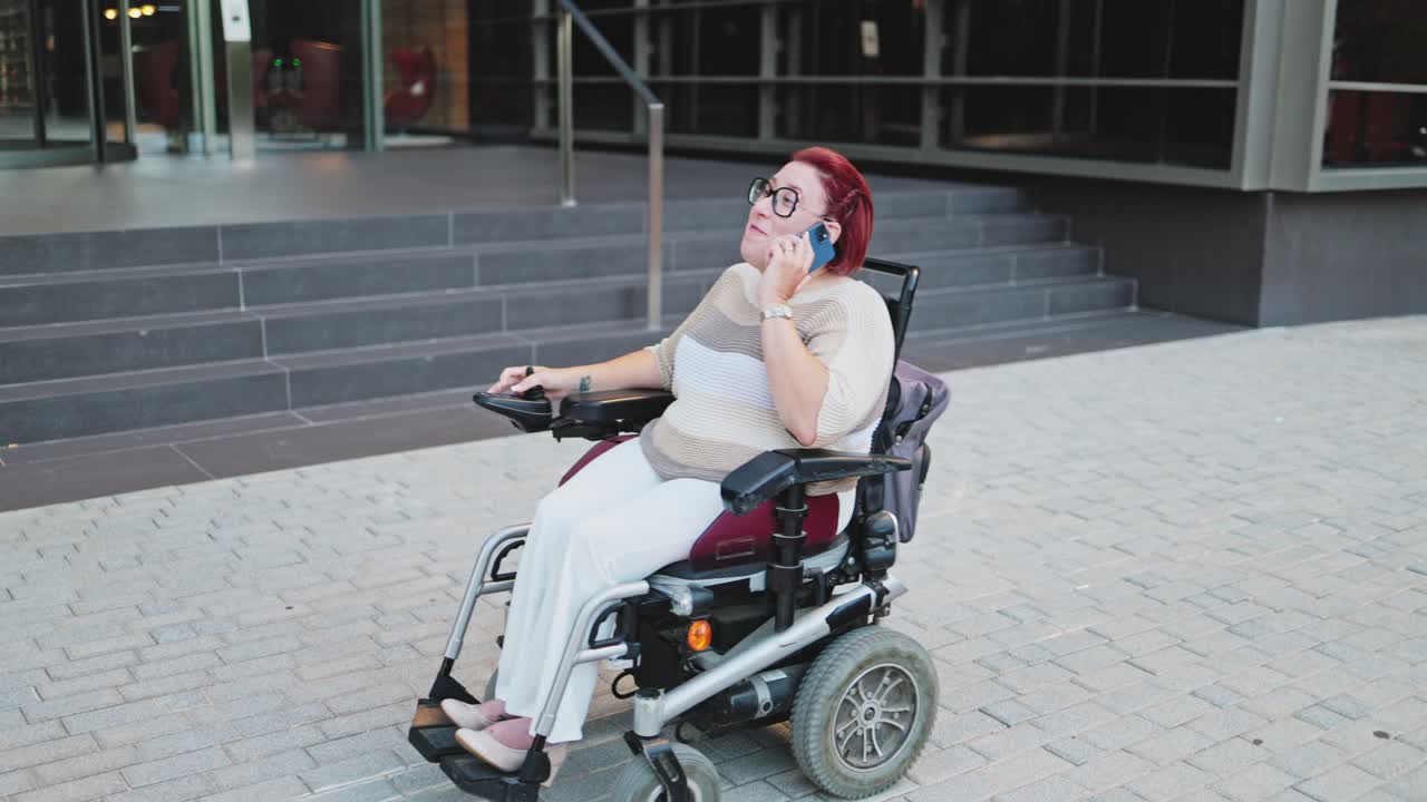 Happy Woman in Electric Wheelchair Talking on Mobile Phone Outdoors