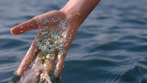 close up hand holding glitter touching sea water splashing creative art concept