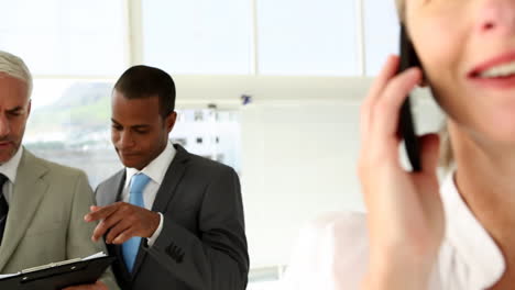 Businesspeople-discussing-and-businesswoman-talking-on-phone