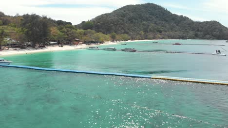 Beautiful-Paradisiac-landscape-of-Banana-Beach-with-shallow-clear-waters-crossed-by-float-Piers---Aerial-Low-angle-Fly-over-shot