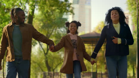 joyful child walking park holding parents hands. cheerful father making jump.