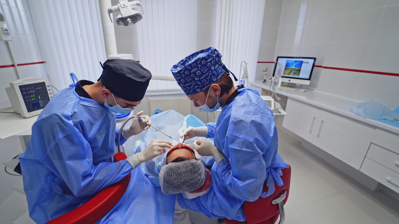 Modern equipment in a dental office. Dentist together with his assistant treat patient's teeth. Stomatologist in blue medical uniform at work.
