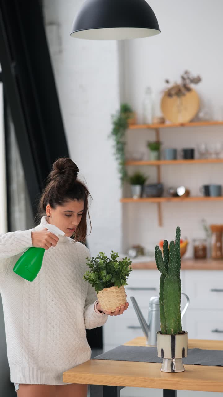 mujer regando plantas en una cocina moderna