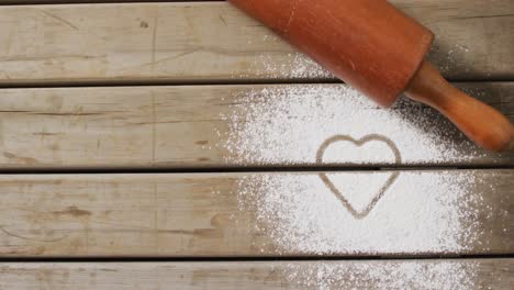 Video-of-rolling-pin-and-heart-shape-in-flour-on-wooden-surface