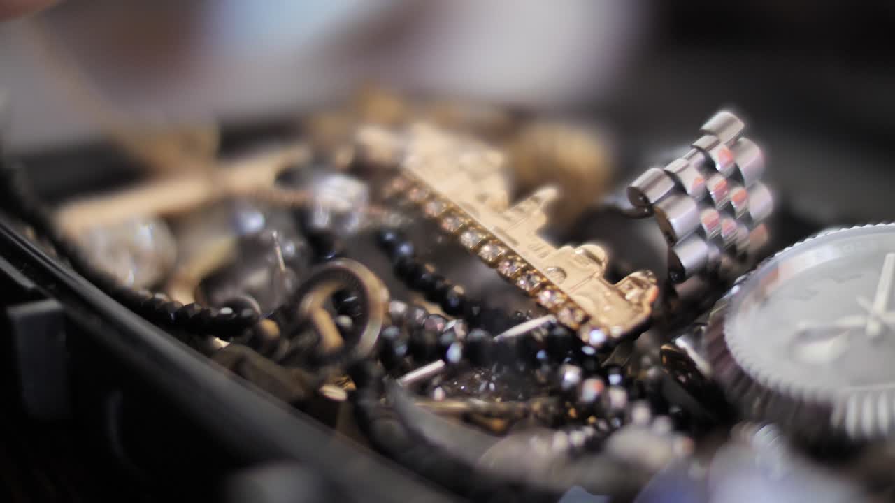 Man fingers pick up golden brooch from menswear jewelry collection, close up