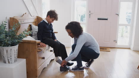 single mother at home getting son wearing uniform ready for first day of school