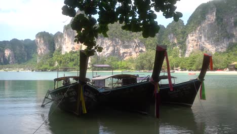 Three-traditional-Thai-boats-are-docked-at-a-tourist-bay-in-Thialand's-Krabi-Province-on-a-sunny-day