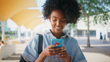 mujer joven enviando mensajes de texto por teléfono al aire libre