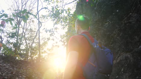 excursionista libre con mochila en el borde de la montaña mirando el sol y disfrutando de una hermosa puesta de sol. viajero feliz hombre en los rayos del amanecer. hombre concepto de sueño. sol resplandor puesta de sol movimiento lento