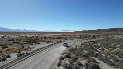 Aerial-view-of-a-car-traveling-in-the-wild-Andes-mountain-terrain,-Deserted-landscape,-Argentina