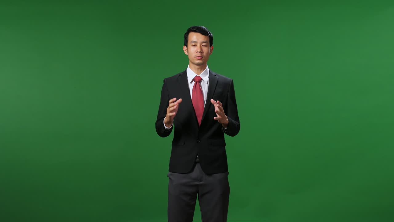 Young Asian Businessman In Suit Jacket Standing And Presenting Something On Green Screen Background