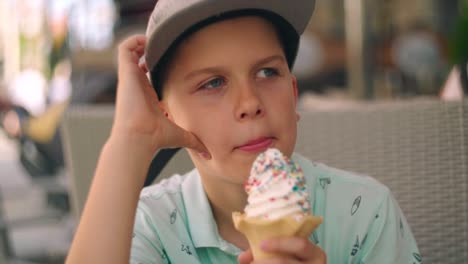 portrait of blond caucasian boy eating and enjoying creamy cold ice cream in a waffle cone