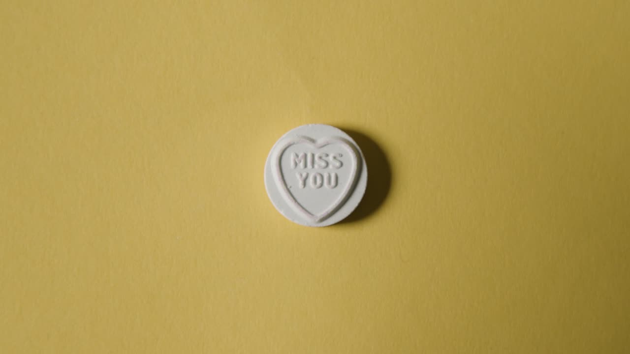 노란색 배경에 당신이 그리워요 메시지와 함께 심장 사탕을 손에 들고