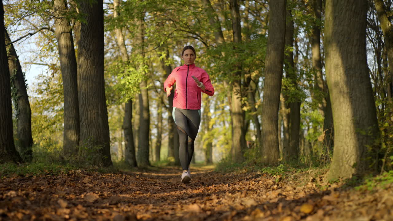 Donna che fa jogging attraverso una foresta autunnale