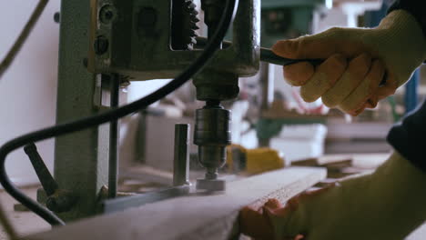 carpintero perfora un agujero en la madera usando una máquina