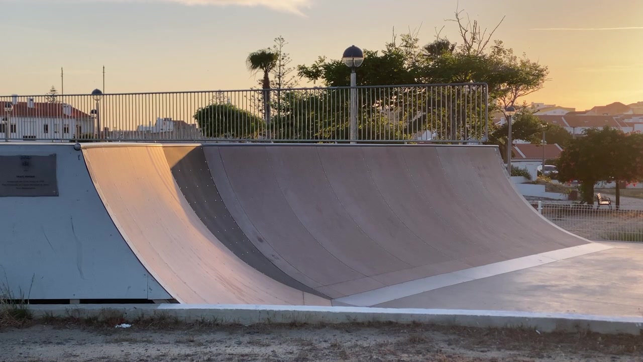 Concrete skatepark ramp reflecting warm light from a beautiful golden hour sunset, showing an urban leisure spot