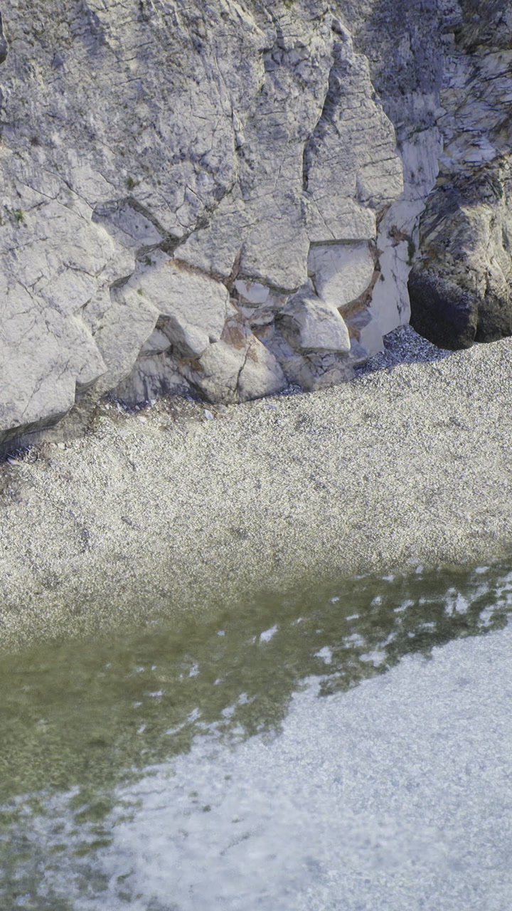 Rocky shore with shallow water and pebbles near the beach during daytime
