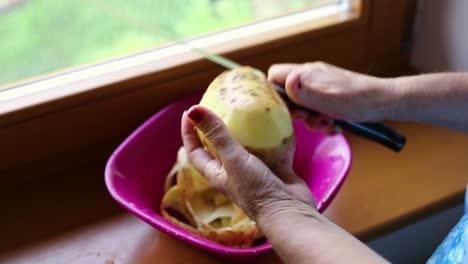 pelar y cortar la patata con un cuchillo con las manos arrugadas