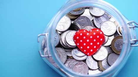 Red-heart-and-coins-in-a-jar-on-white-background