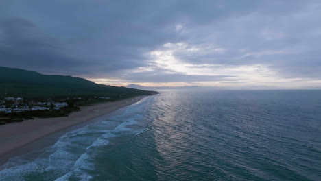 Aerial-view-over-a-beach,-dramatic-cloudy-evening-on-the-coastline-of-Spain