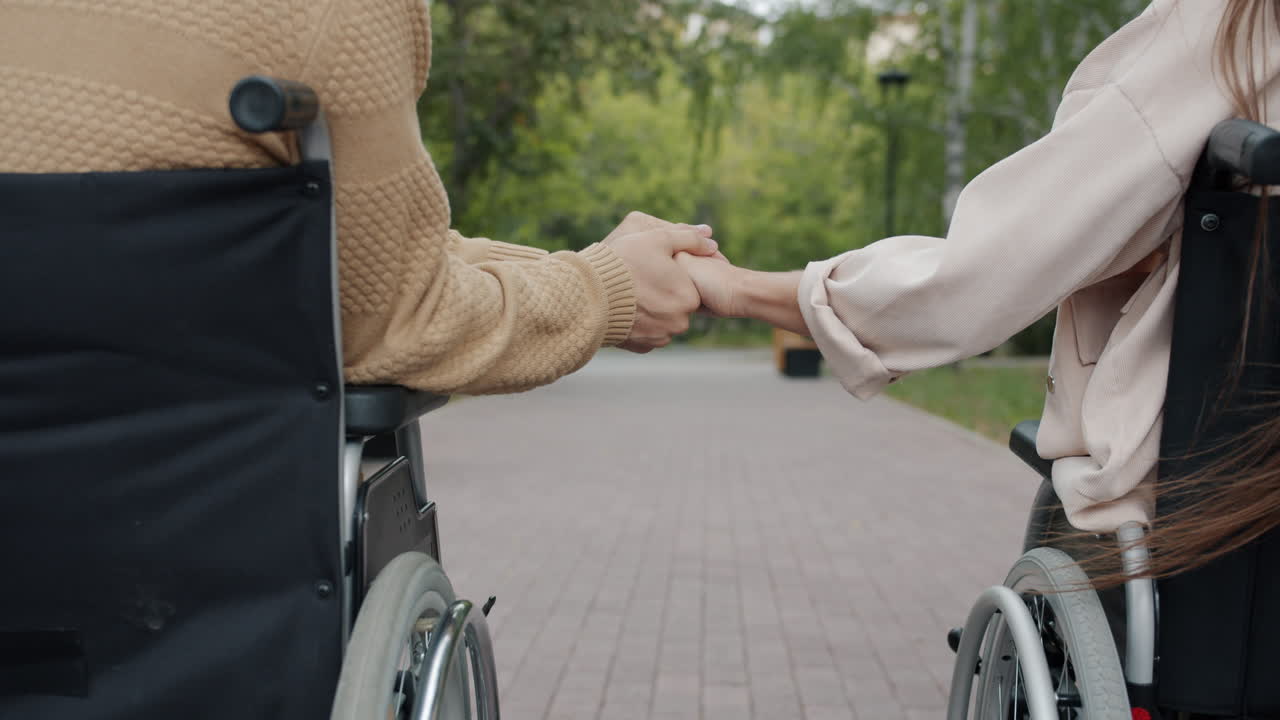 Couple in Wheelchairs Holding Hands in Park