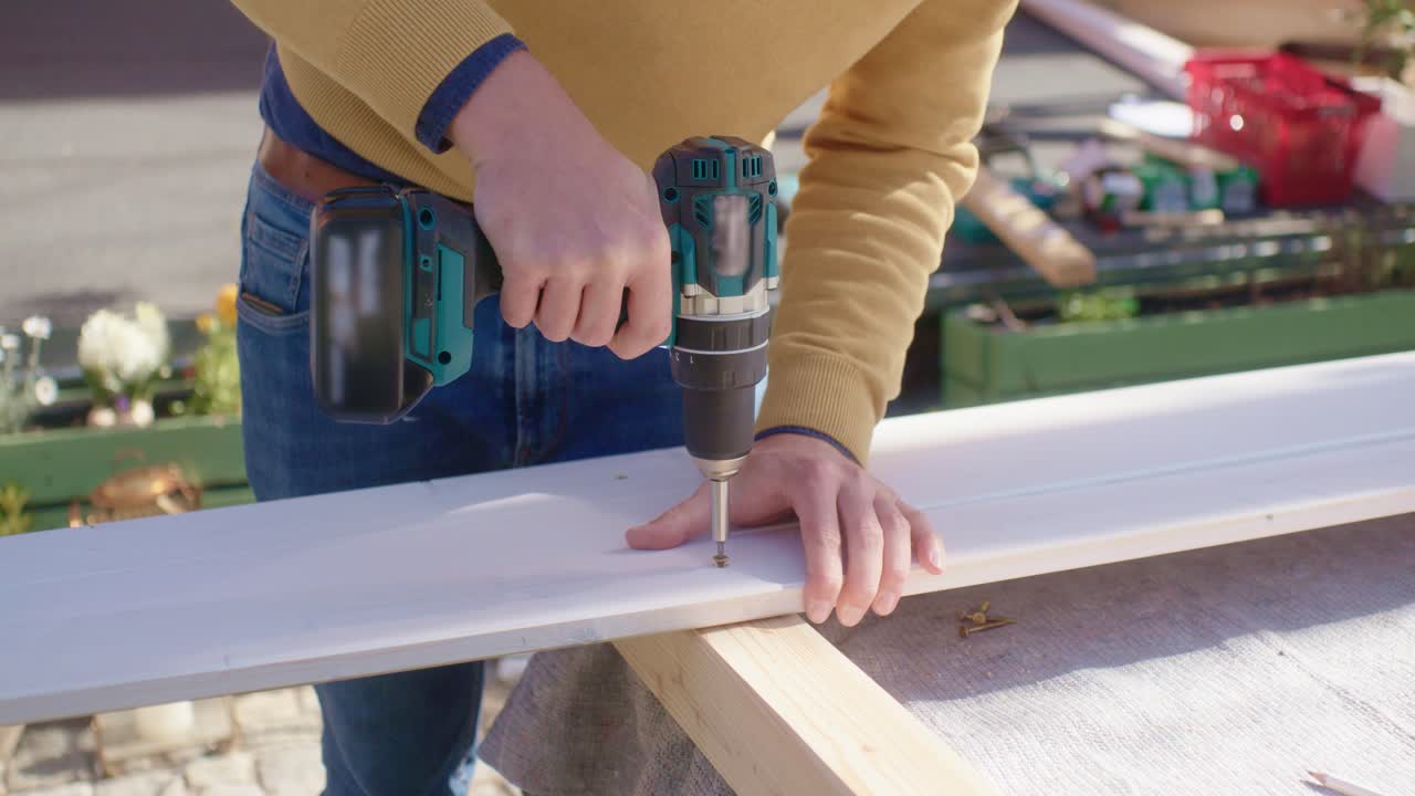 The craftsman screwing the screw with a cordless screwdriver