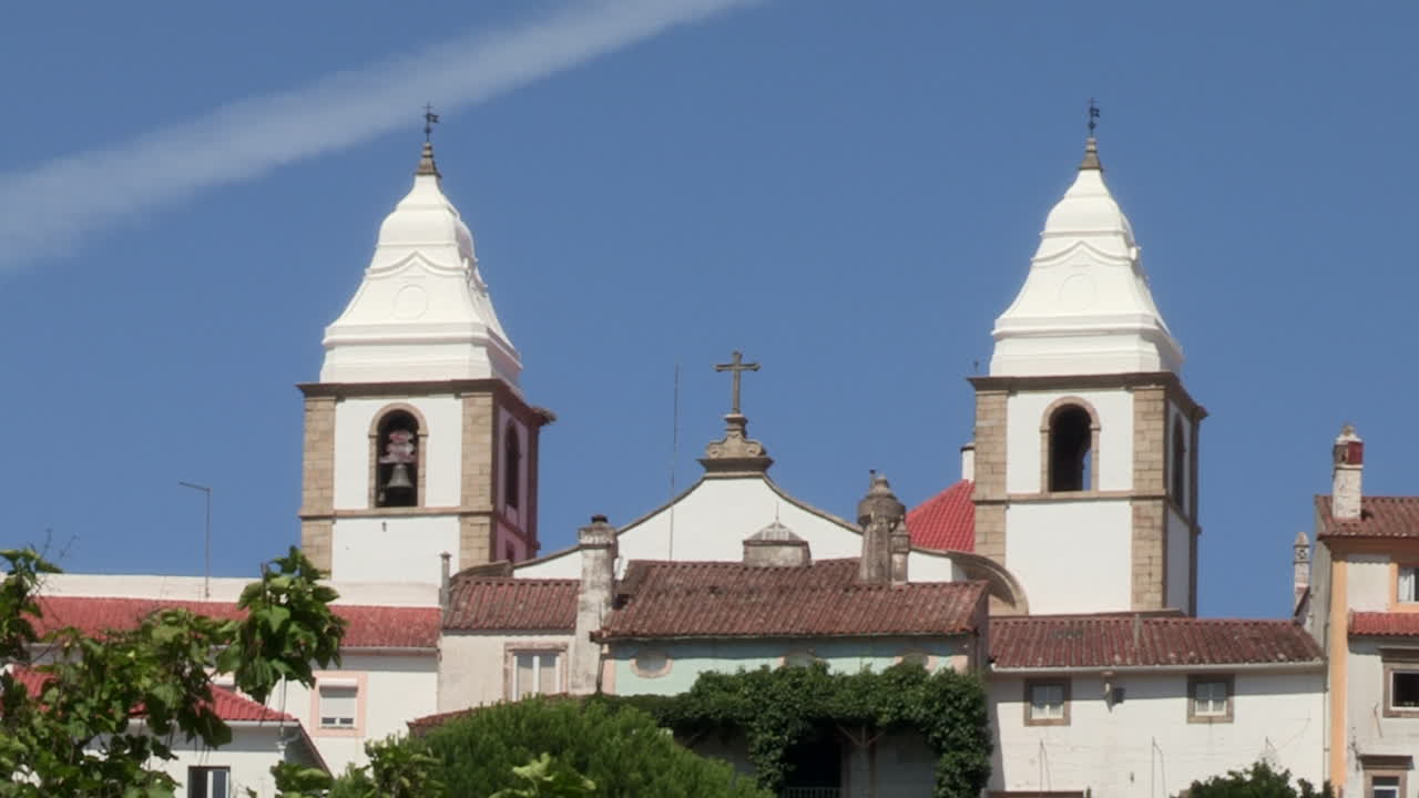 las dos torres blancas de la iglesia de santa maría da devesa en el medio en la parte superior del pueblo