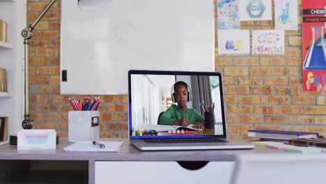 Webcam-view-of-african-american-school-boy-on-video-call-on-laptop-on-table-at-school