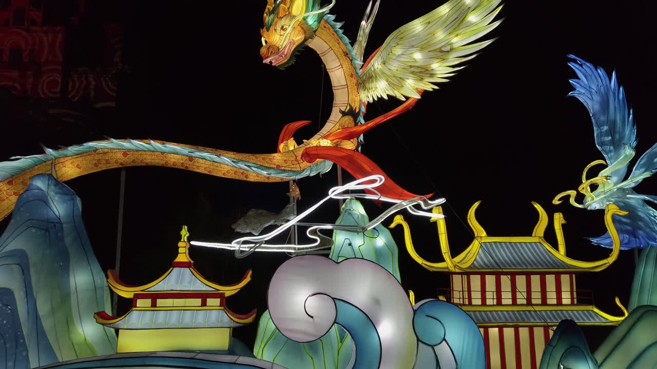 Illuminated dragon and phoenix lanterns glowing above stylized mountains, showcasing vibrant chinese artistry at splendeurs de la chine light festival in france