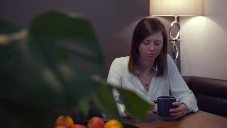 A-sad-upset-young-woman-sitting-at-home-drinking-coffee-looking-pensive-alone-and-lonely