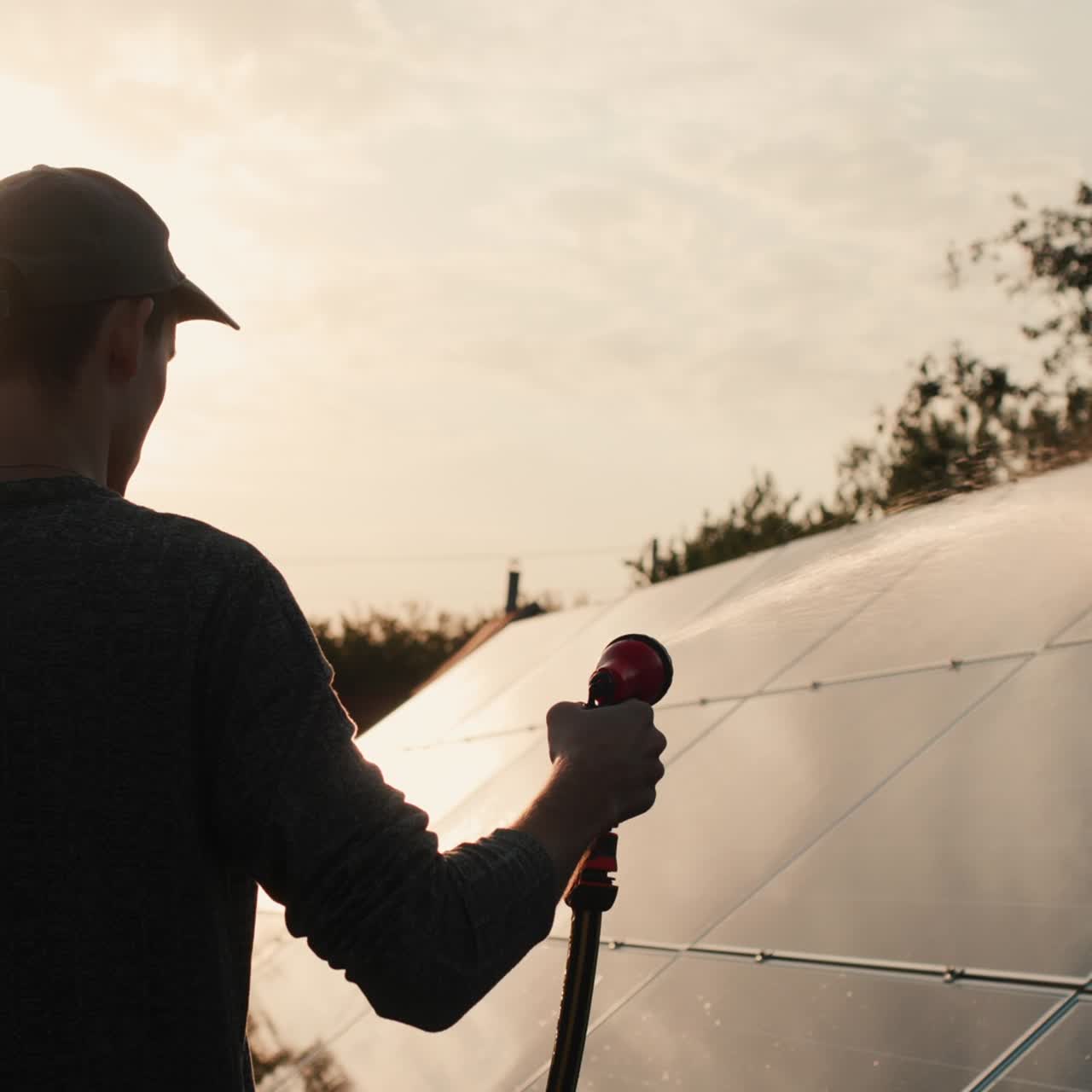 silueta de un hombre lavando un panel de planta de energía solar