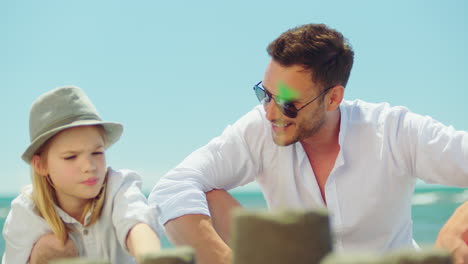 father and daughter building sandcastles on the beach