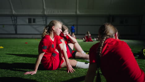 female soccer players sitting on the field during a break