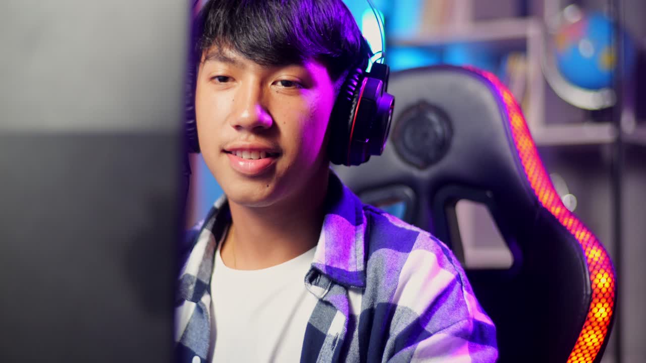 컴퓨터에서 비디오 게임을 하는 동안 카메라에 미소 짓는 아시아 십대 소년 게이머의 클로즈업