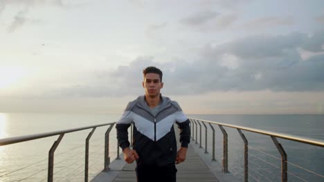 joven atleta atractivo corriendo hacia la cámara en un puente por la mañana desde un punto de vista en cámara lenta