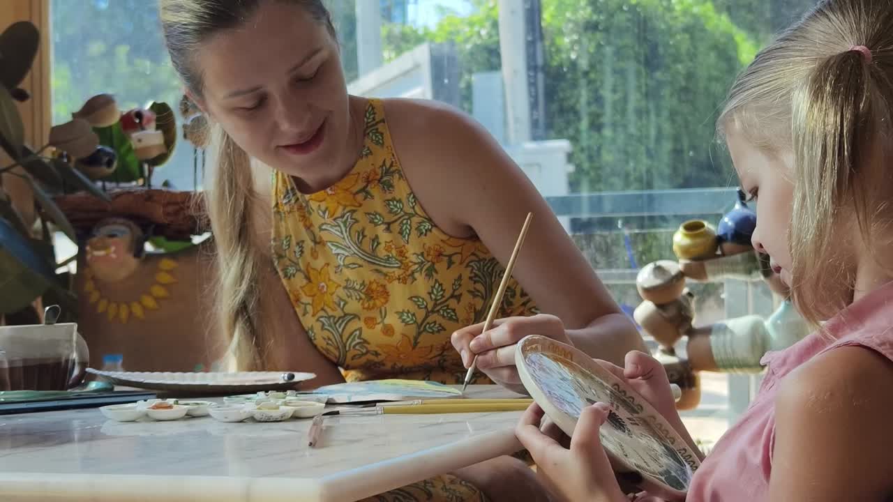 Mother and daughter painting pottery at a cafe