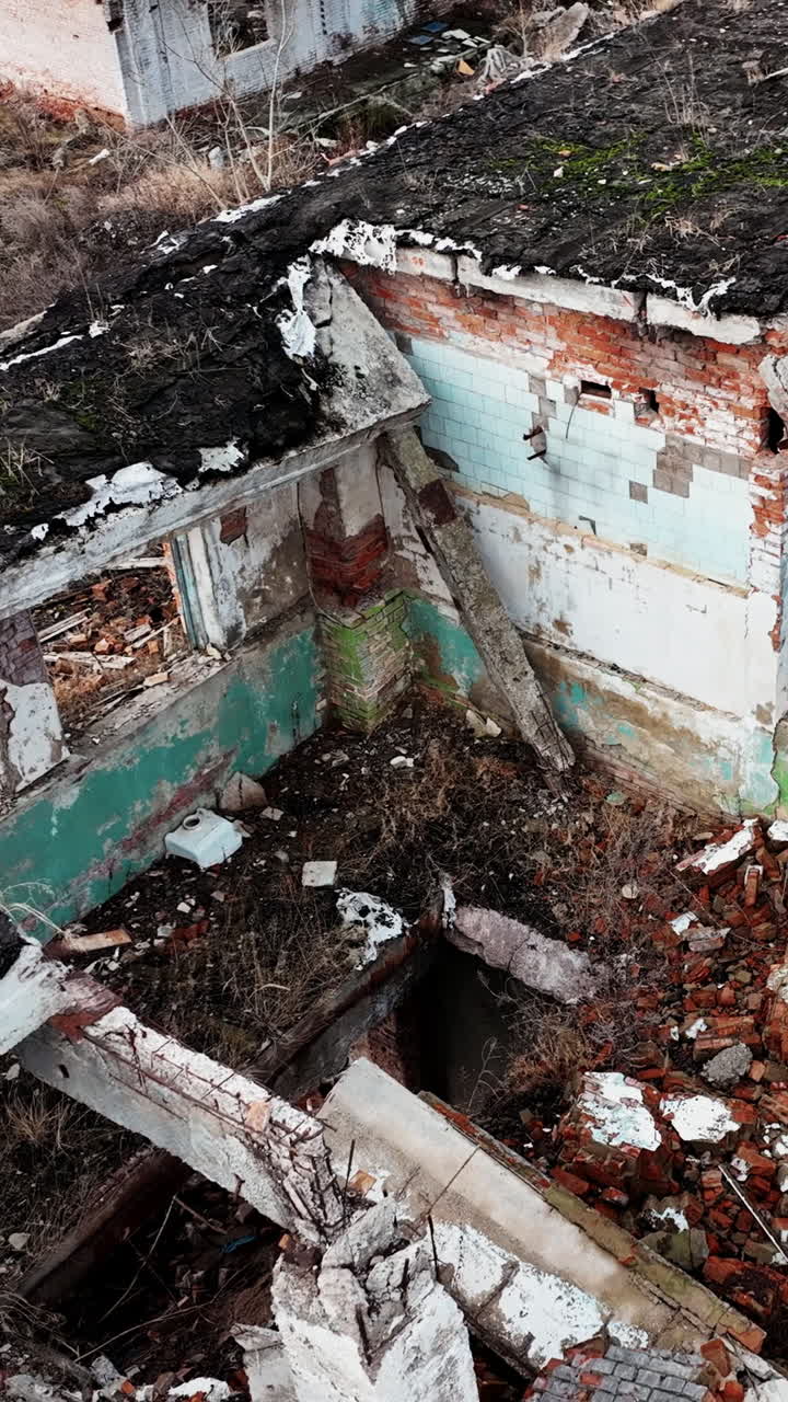Ruins and wrecks of a destroyed urban territory. Demolished area with buildings into rubble after a natural disaster. Aerial view. Vertical video