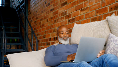 Senior-man-using-laptop-in-living-room-4k